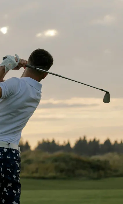 Male golfer in mid-swing on a golf course at sunset, symbolizing elite athletic performance and global ambition – banner image for Hogan Lovells and GSE Worldwide case study